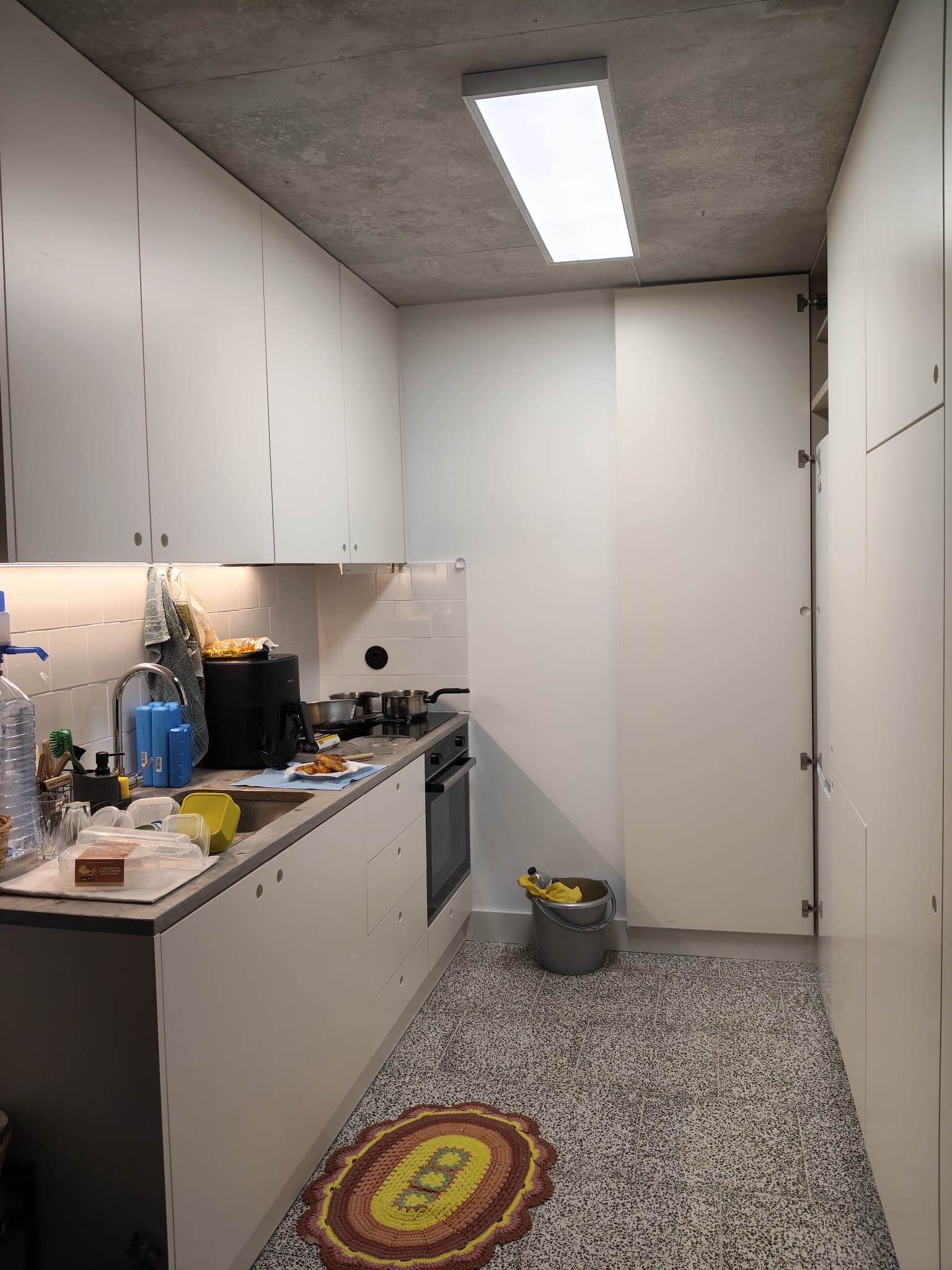 Cozinha compacta remodelada com armários brancos feitos à medida e iluminação integrada
