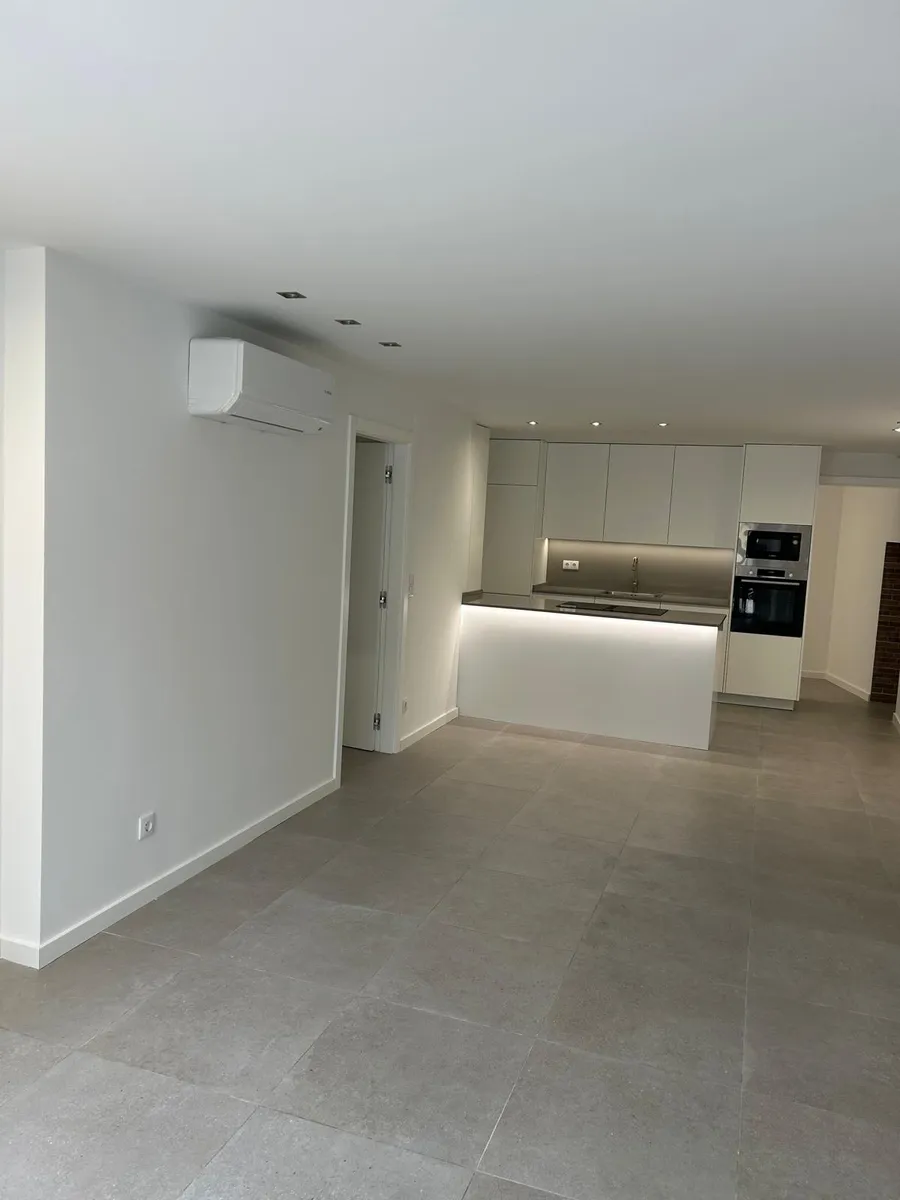 Cozinha moderna branca com ilha central e pavimento cinzento